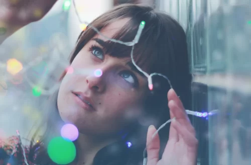 woman holding holiday lights looking at them in wonder